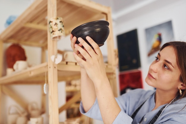 Il lavoro è terminato Giovane ceramista al chiuso con prodotto finito a mano in argilla Concezione della ceramica