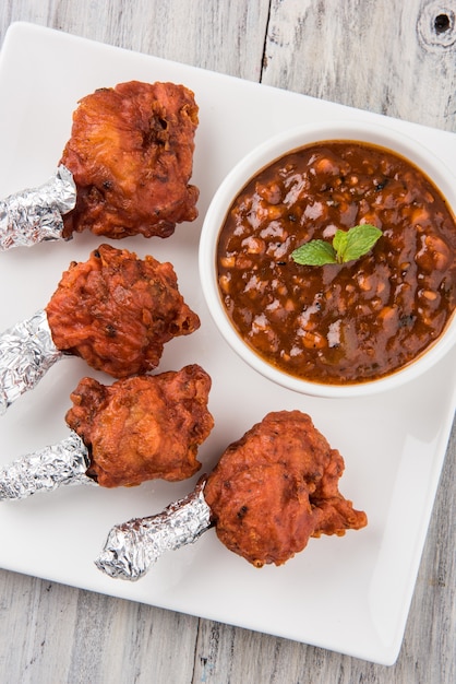 Il lecca-lecca di pollo è un antipasto cinese indiano che è un'ala di pollo alla francese. avvolto con un foglio d'argento ad un'estremità e sopravvissuto con chutney. Su sfondo colorato o in legno. Messa a fuoco selettiva.