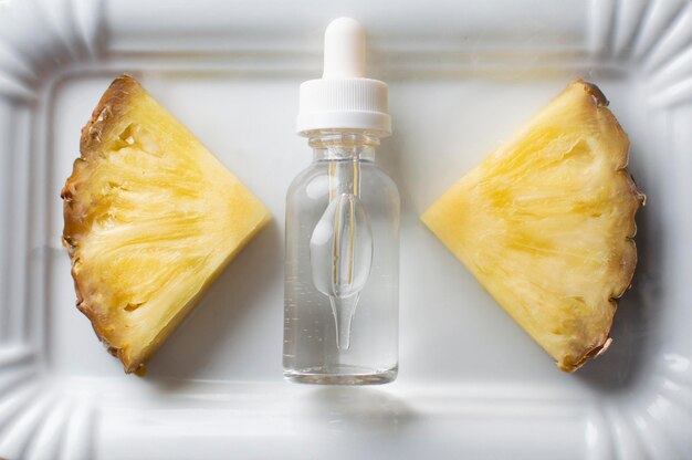 Il liquido vape aromatizzato all'ananas si trova su un piatto bianco con due pezzi di ananas