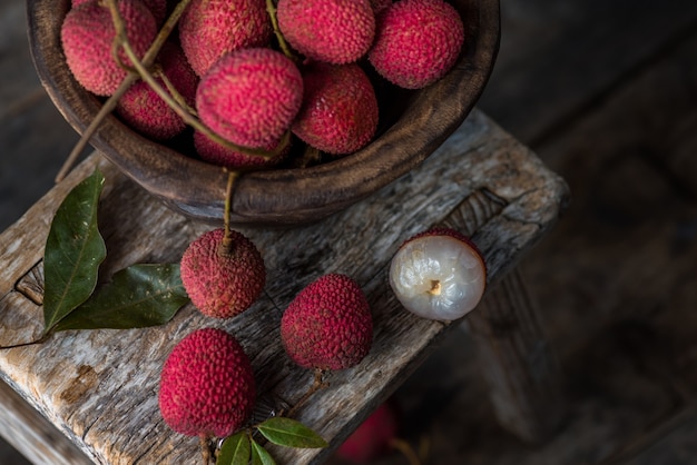 Il litchi è posto in un piatto di legno, sbucciato o non aperto, su un tavolo con venature di legno scuro