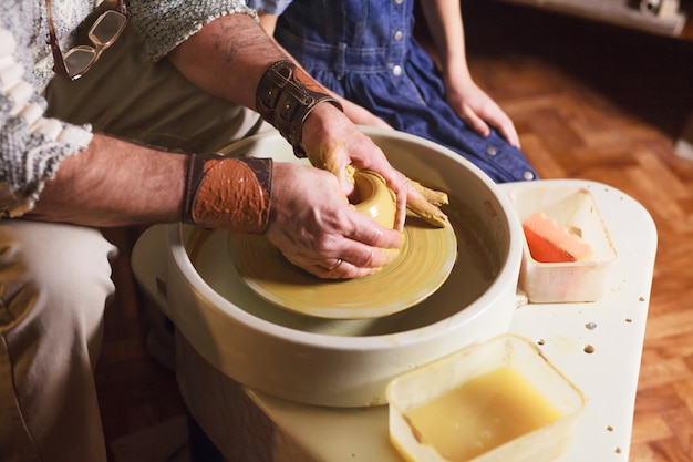 Il maestro con il bambino modella una brocca di terracotta.