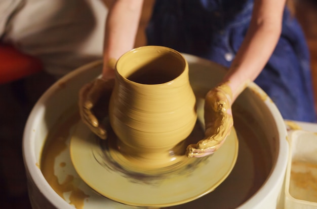 Il maestro con il bambino modella una brocca di terracotta.