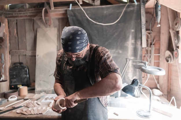 Il maestro del cucchiaio nella sua bottega con prodotti e strumenti in legno. Foto di alta qualità