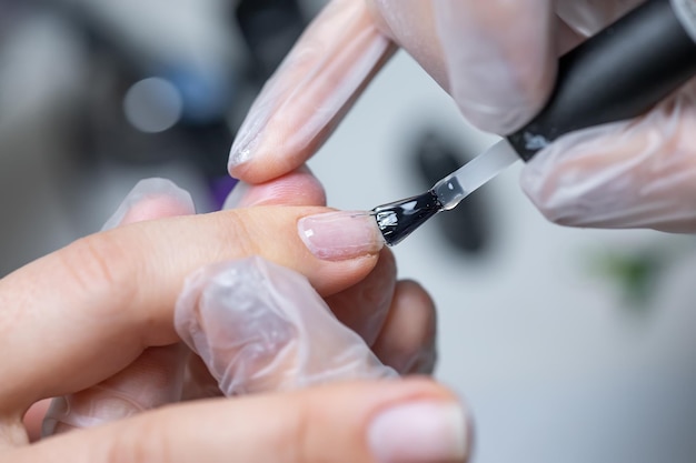 Il maestro del servizio unghie fa una manicure per applicare il gel con un pennello sull'unghia trattata