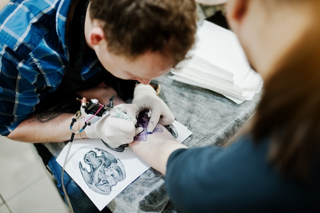 Il maestro del tatuaggio fa il tatuaggio per l'uomo rocker