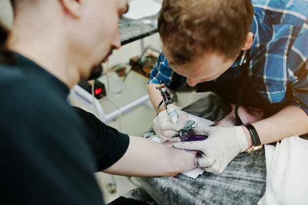 Il maestro del tatuaggio fa il tatuaggio per l'uomo rocker