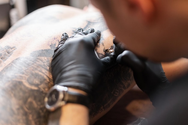 Il maestro del tatuaggio in guanti neri fa un tatuaggio, primo piano