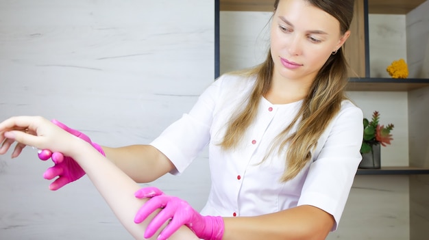 Il maestro della depilazione con cera e zucchero tiene la mano del cliente e la spalma con una crema idratante dopo la procedura