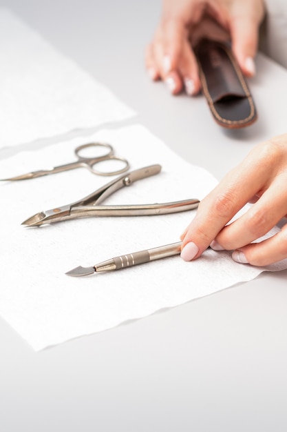 Il maestro di manicure espone il set di manicure su un asciugamano al tavolo in un salone di bellezza