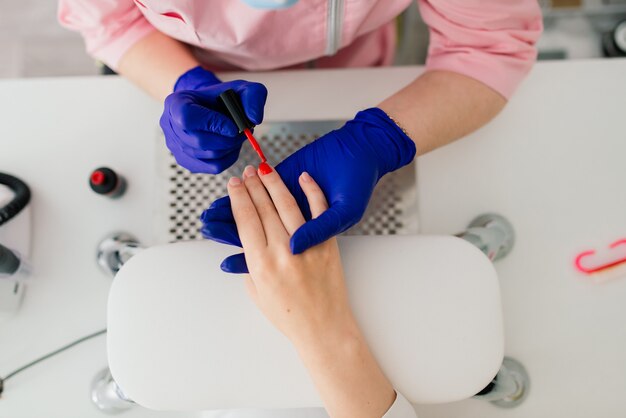 Il maestro di manicure femminile in un salone di bellezza lavora con le mani del cliente