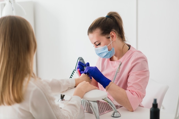 Il maestro di manicure femminile in un salone di bellezza lavora con le mani del cliente