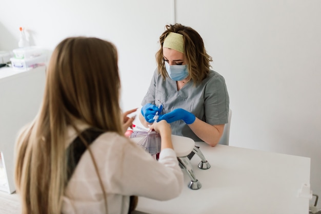 Il maestro di manicure femminile in un salone di bellezza lavora con le mani del cliente