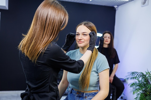 Il maestro segna il viso della donna prima del trucco permanente delle sopracciglia Tatuaggio delle sopracciglia Procedura di bellezza per il viso di una donna