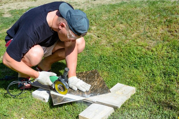 Il maestro stuccatore taglia la piastrella di marmo attorno al disco ceramico