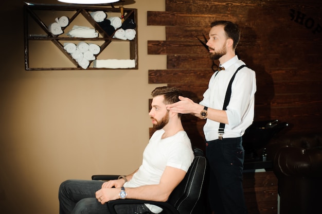 Il Maestro taglia i capelli e la barba degli uomini nella bottega del barbiere