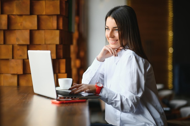 Il manager di successo della giovane donna sta parlando tramite telefono cellulare con un possibile dipendente della società finanziaria e sta leggendo il loro curriculum sul computer portatile portatile durante il colloquio remoto nello spazio di co-working