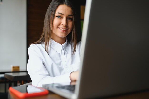 Il manager di successo della giovane donna sta parlando tramite telefono cellulare con un possibile dipendente della società finanziaria e sta leggendo il loro curriculum sul computer portatile portatile durante il colloquio remoto nello spazio di co-working