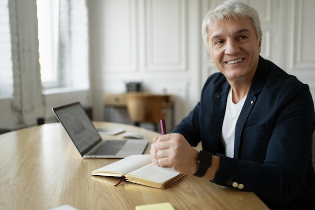 Il manager gray presenta una relazione all'azienda Un uomo maggiorenne lavora in un ufficio Posto di lavoro in un coworking