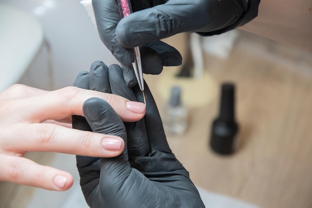 Il manicure livellare il bordo della vernice con un pennello sottile in un salone