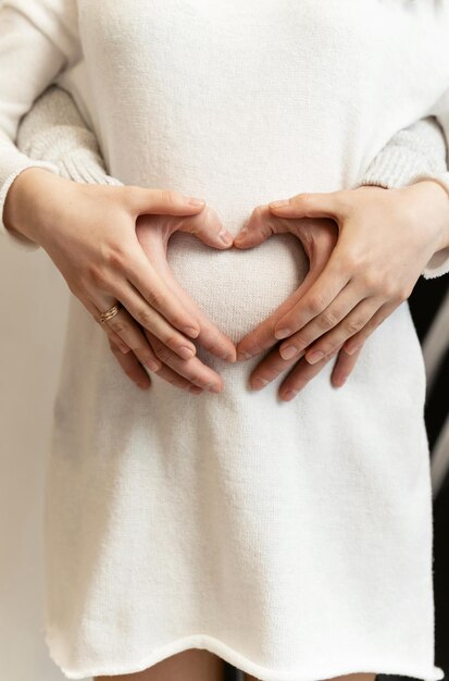 Il marito abbraccia la moglie incinta. primo piano del cuore sulla pancia di una donna incinta.futuri genitori