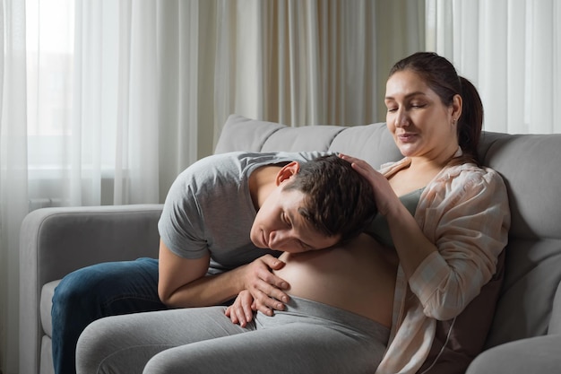 Il marito accarezza e bacia lo stomaco incinta della moglie sul divano