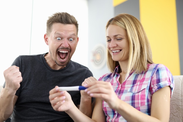 Il marito e la moglie sorridenti stanno esaminando il test di gravidanza