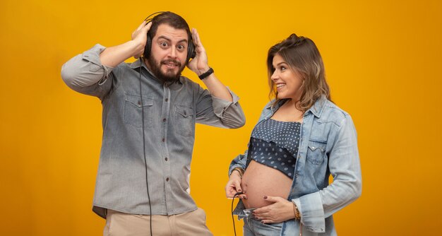 Il marito gioca ascoltando il figlio che batte la pancia della moglie usando le cuffie.