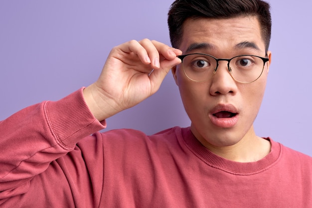 Il maschio cinese bello scioccato in occhiali reagisce emotivamente a qualcosa con la bocca aperta