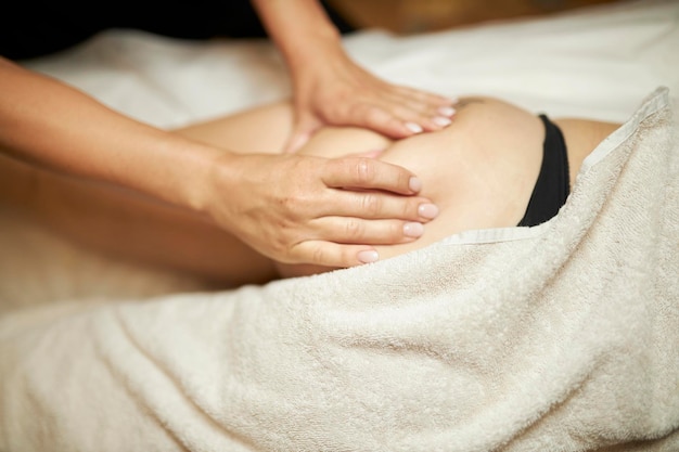 Il massaggiatore effettua un massaggio anticellulite dei glutei ad un massaggio anticellulite femminile