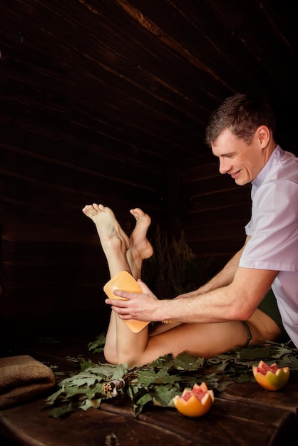 Il massaggiatore fa un massaggio ai piedi a una ragazza nella sauna