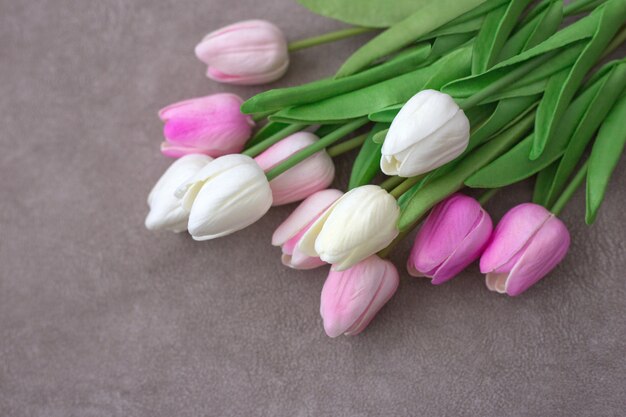 Il mazzo dei tulipani rosa e bianchi si trova sulla tavola marrone