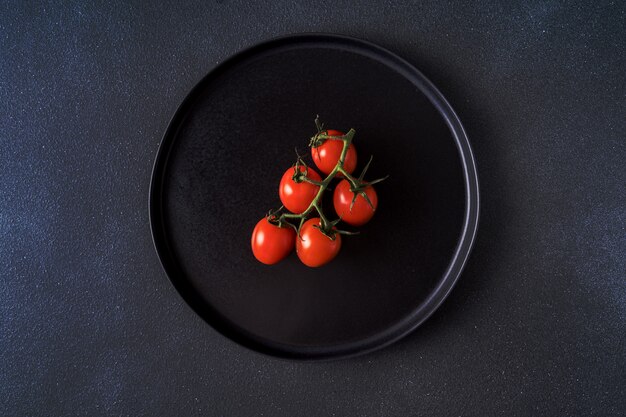 Il mazzo di pomodoro ciliegia rosso è servito sulla banda nera