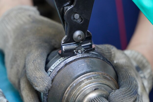 Il meccanico assembla una copertura in gomma per un assale di un'auto in un centro di assistenza Attrezzo morsetto CV e cuffia giunto CV