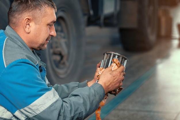 Il meccanico automatico ripara il camion Riparazione e diagnostica professionali di trattori e attrezzature da carico Il meccanico in officina considera i pezzi di ricambio