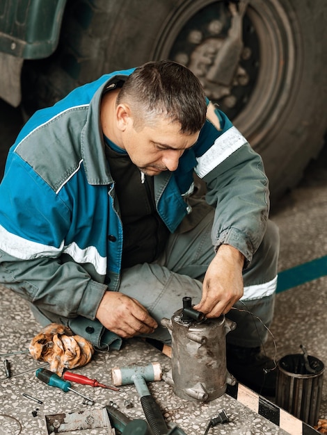 Il meccanico automatico ripara il camion Riparazione e diagnostica professionali di trattori e attrezzature da carico Il meccanico in officina considera i pezzi di ricambio