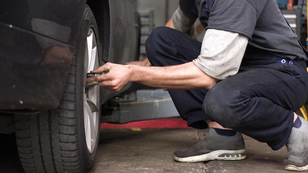 Il meccanico automobilistico fa girare la ruota dell'officina dell'auto