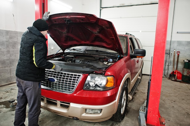 Il meccanico automobilistico imposta l'auto SUV americana per la diagnostica e la configurazione nella stazione di servizio dell'officina