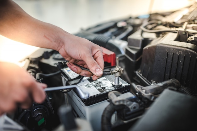 Il meccanico dell'auto sta per rimuovere la batteria per sostituire la nuova batteria dell'auto nell'officina riparazioni.