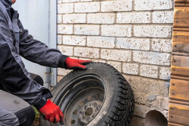 Il meccanico di auto maschio in tuta ispeziona la ruota di un'auto