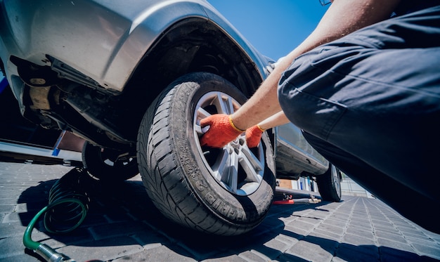 Il meccanico di automobile professionista sostituisce la gomma sulla ruota.