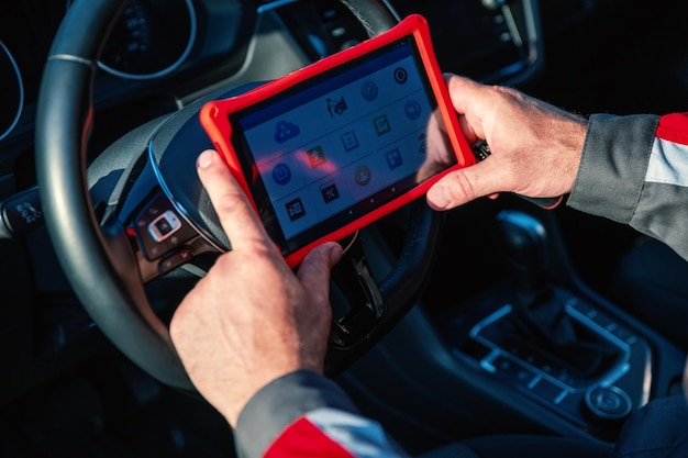 Il meccanico di automobili tiene il tablet per il controllo dei sistemi elettronici delle automobili