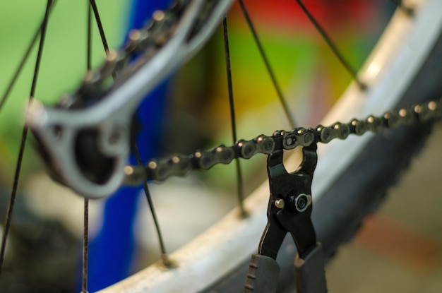 Il meccanico di biciclette in officina durante il processo di riparazione tiene lo strumento in mano Sostituzione della catena della bicicletta