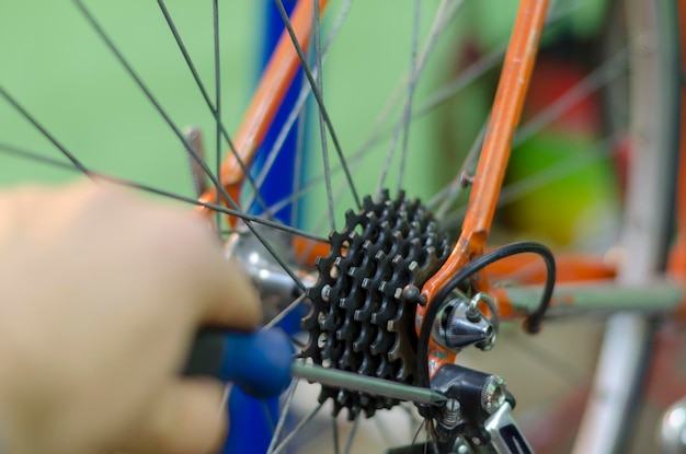 Il meccanico di biciclette in un'officina nel processo di riparazione tiene uno strumento in mano