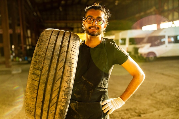 Il meccanico ispanico latino in uniforme sta esaminando un'auto mentre lavora nel servizio auto