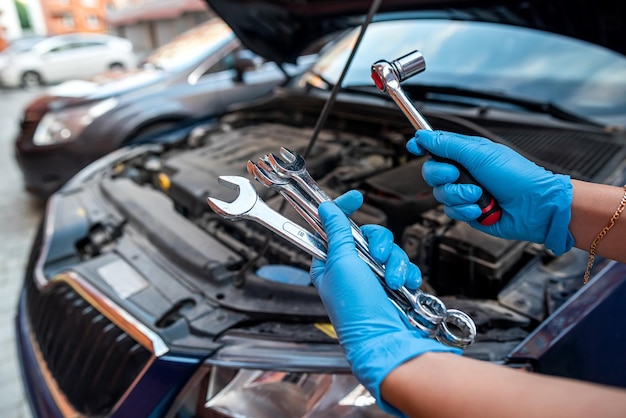 Il meccanico o il riparatore di automobili ripara a mano il motore di un'auto in un'officina automobilistica con un servizio di assistenza per auto chiave e servizi di riparazione di manutenzione