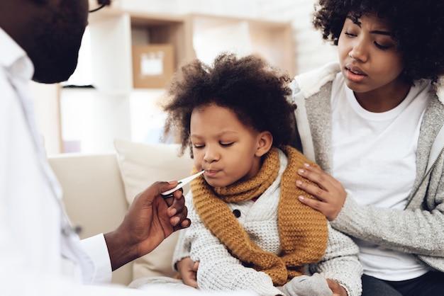 Il medico africano prende la temperatura della ragazza malata con influenza.