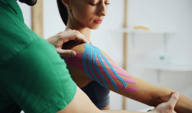 Il medico aiuta la donna curando la spalla con un nastro kinesio