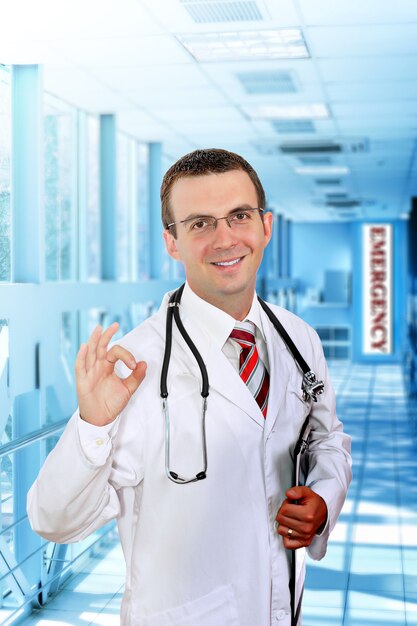 Il medico amichevole sta nel corridoio dell'ospedale, mostra OK!