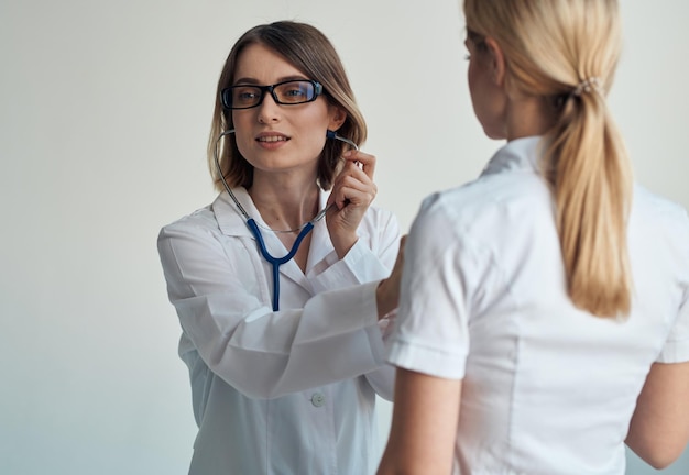 Il medico ascolta il battito cardiaco del paziente attraverso uno stetoscopio su una vista ritagliata di sfondo chiaro