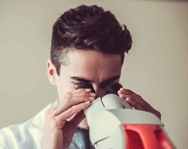 Il medico bello sta usando un microscopio.